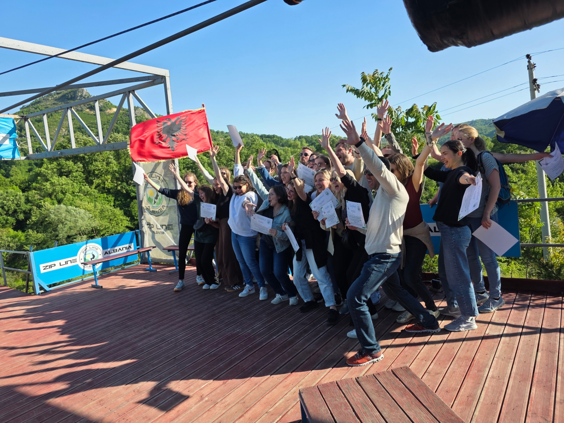 Group celebration on the wooden deck with Albanian flag